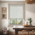 Custom light filtering linen roller shades in neutral linen look, installed in cozy dining area with garden view