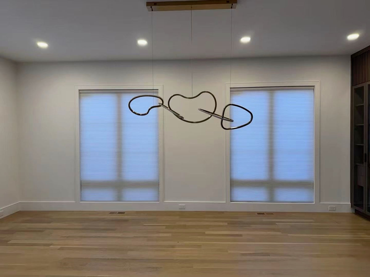 KALIA cellular shades covering two dining room windows beneath a sculptural light