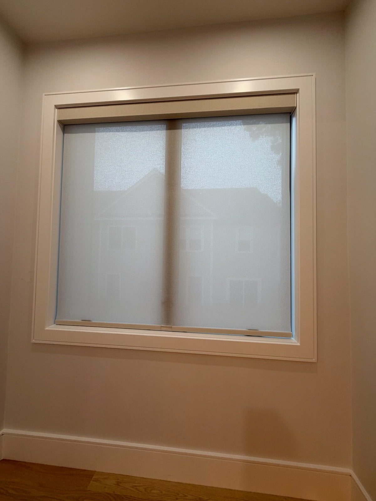 Light filtering KALIA roller shade fitted within a white window frame